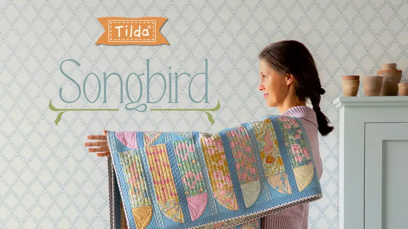 donna che regge un quilt con i tessuto Tilda Songbird